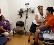 Families soon will be able to sign up for new health insurance options through the Affordable Care Act. In Washington, D.C., Dr. Cheryl Focht of Mary's Center performs a checkup of Jayson Gonzalez, 16, while his mother, Elizabeth Lopez, looks on.